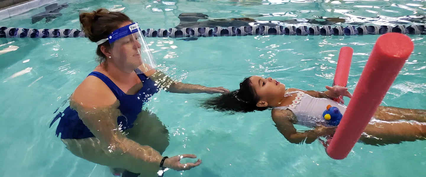 woman teaching child swimming