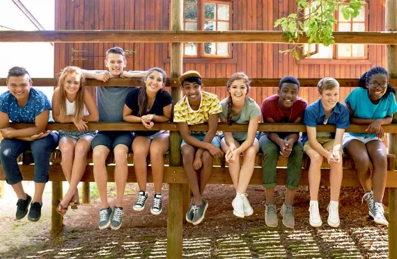 group of kids sitting on a boardwalk