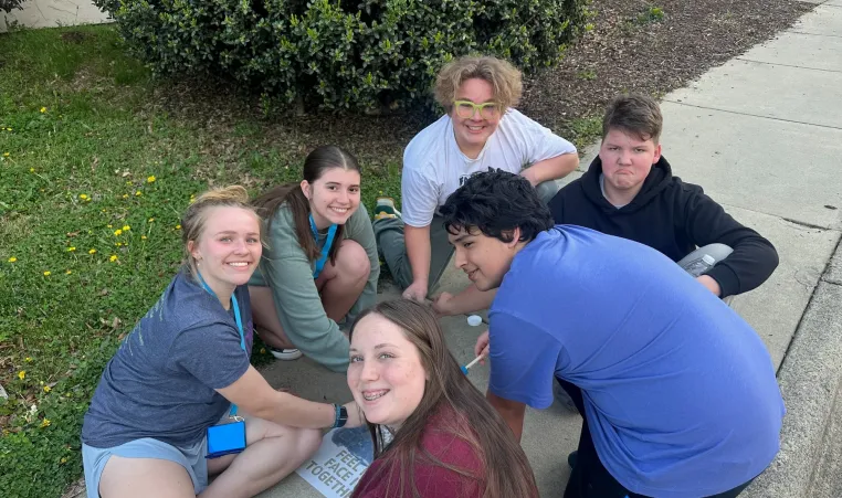 teens painting a QR code stencil on sidewalk to educate people about mental health resources