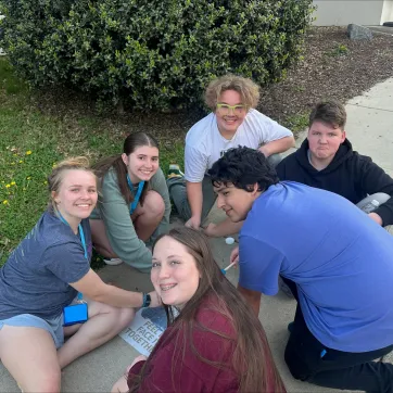 teens painting a QR code stencil on sidewalk to educate people about mental health resources